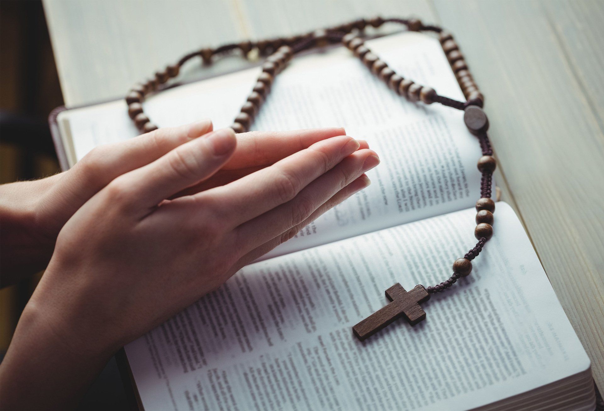 Hand praying with book and rosary