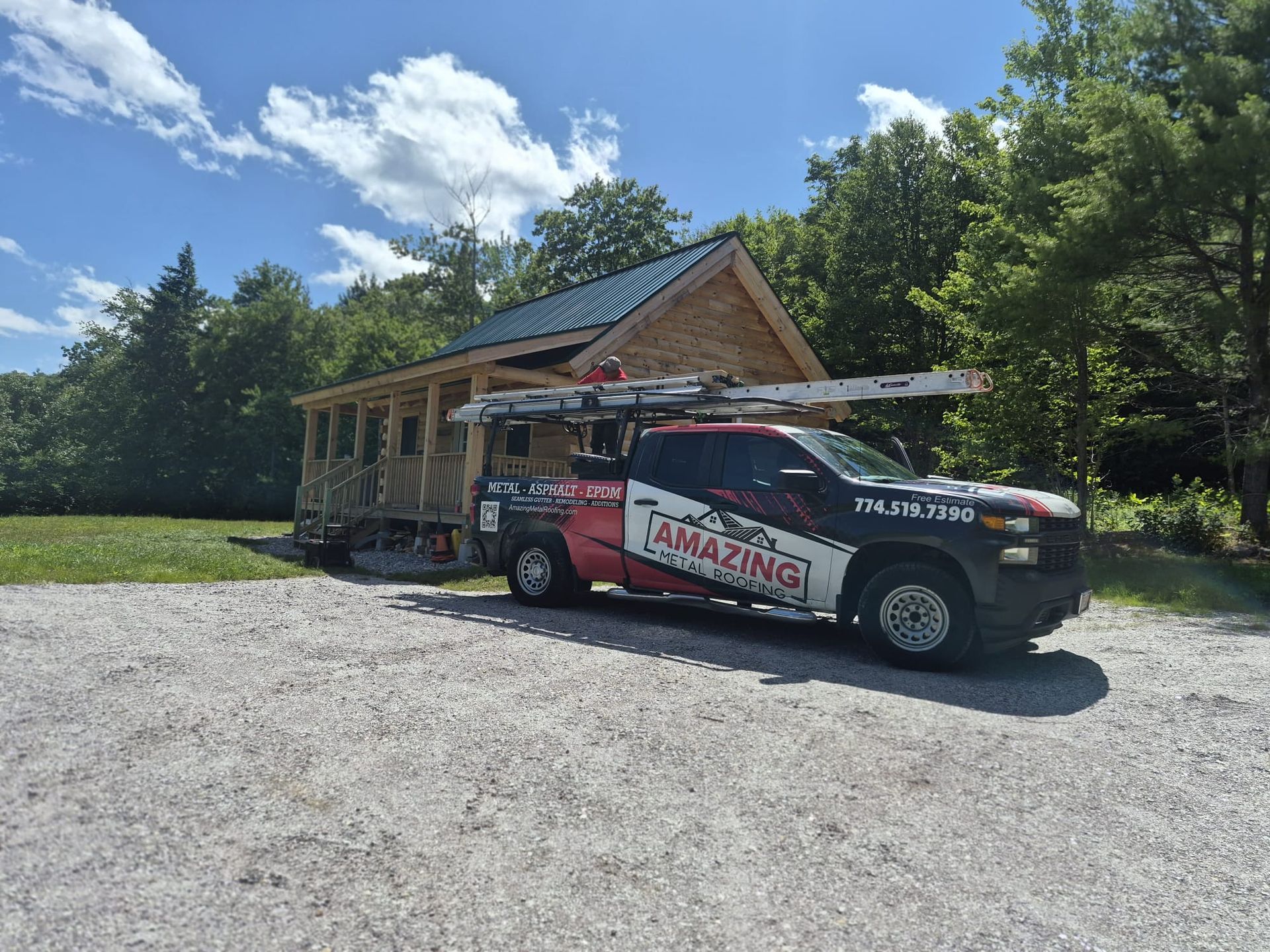 Truck parked outside a rustic building on a sunny day, with a gravel lot and blue sky.