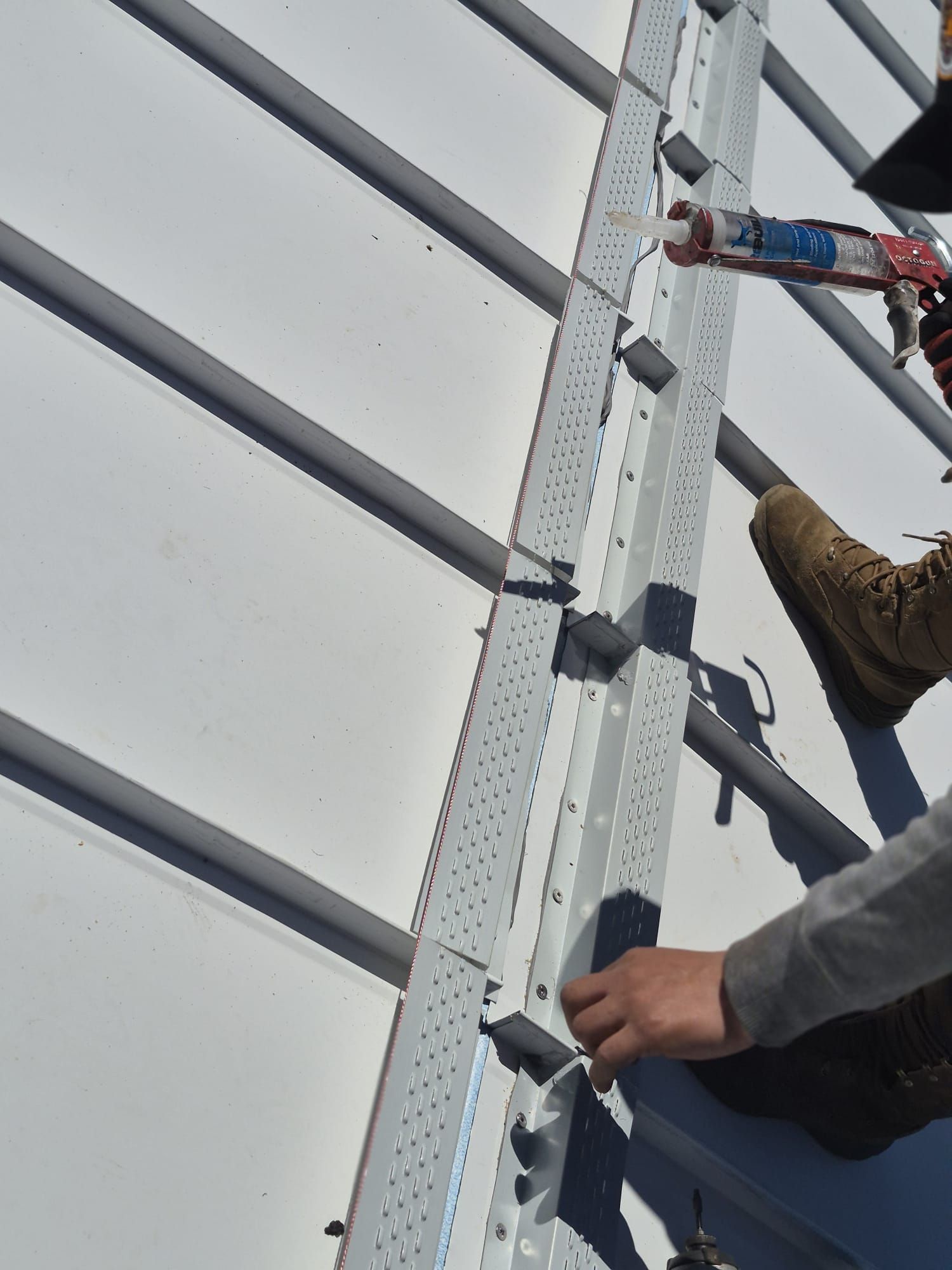 Workers climbing a metal ladder on a building facade during maintenance