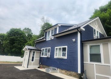 Blue house exterior with white trim and a small entry porch under a cloudy sky