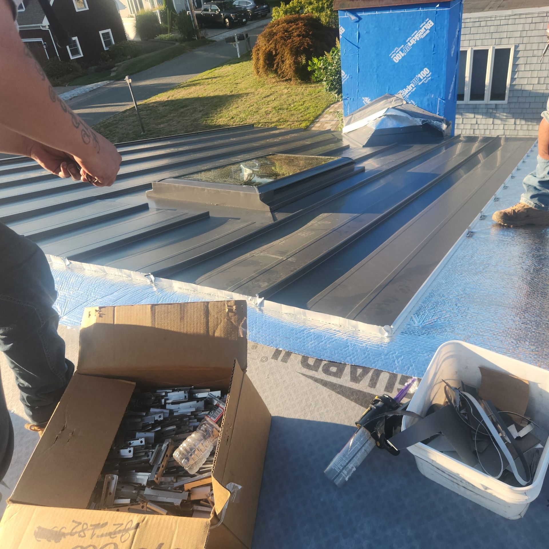 People unloading hardware from a truck on a sunny street, with boxes and tools on the truck bed.