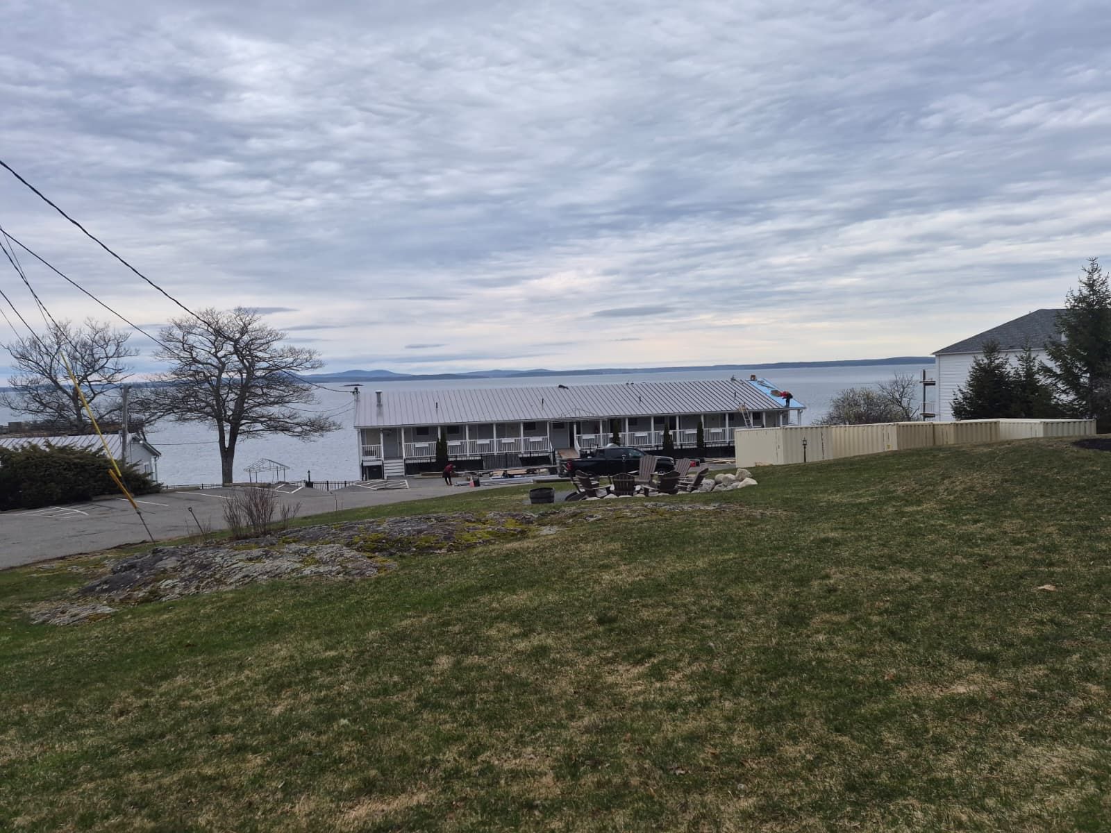 Grassy lakeside overlook with benches and a dock under a cloudy sky