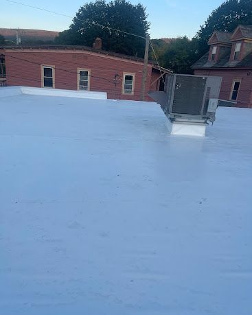 Snow-covered rooftop with brick buildings and a metal railing in the background