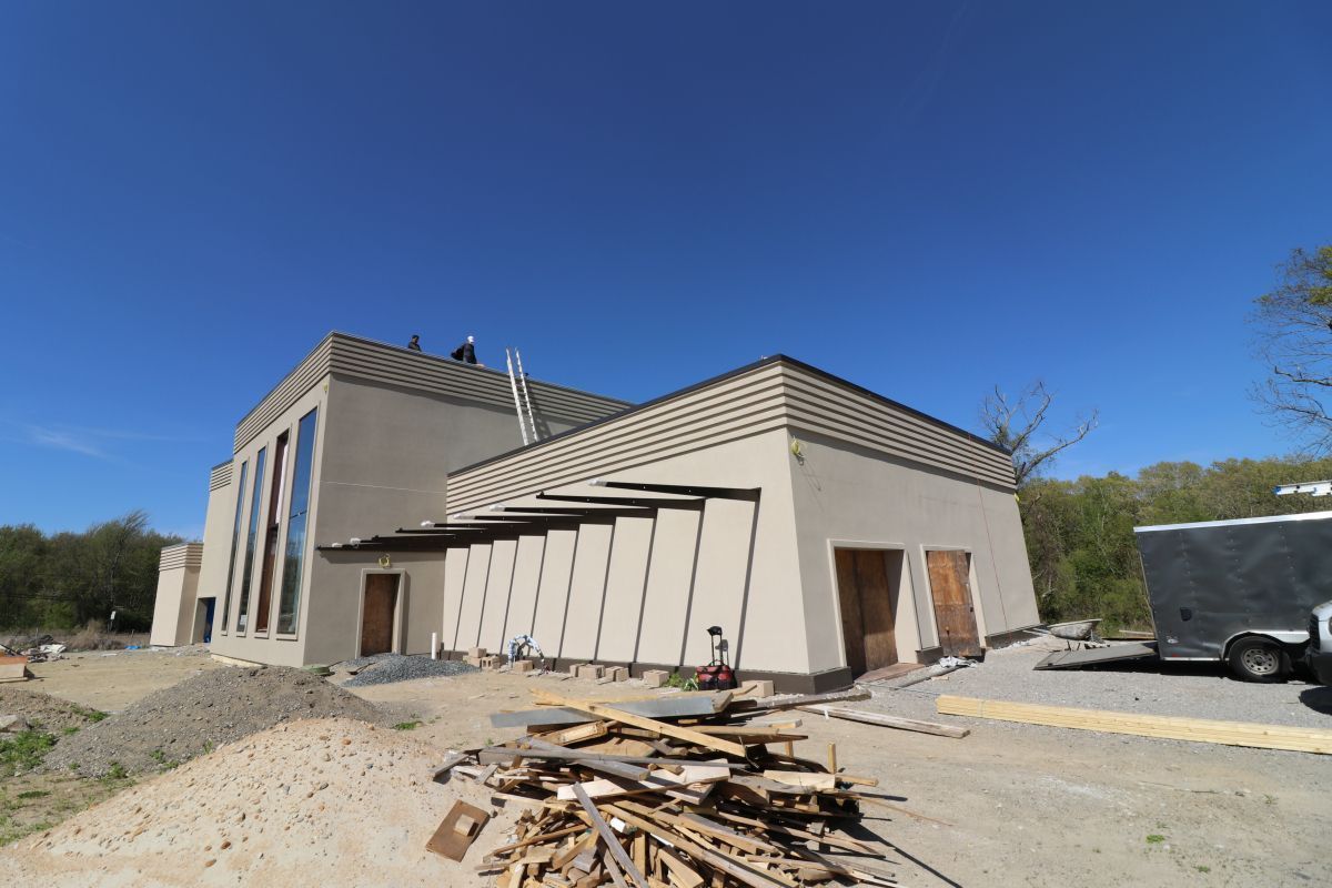 Exterior of a modern building under construction with debris and equipment in front