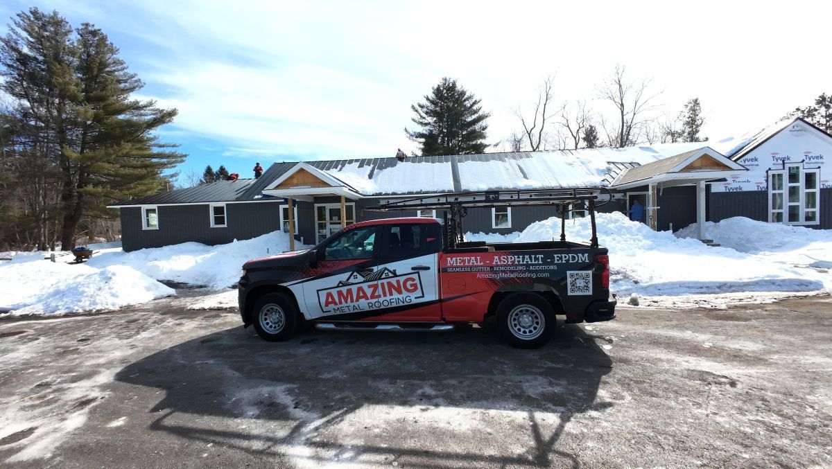 Red-and-black pickup truck parked on a snowy street in front of houses.
