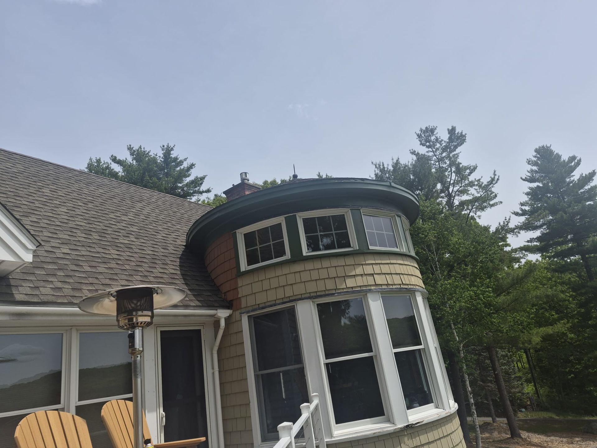 House exterior with rounded bay window and dark shingled roof beneath an overcast sky