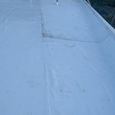 Flat light-gray rooftop with seams and a faint patch, viewed from above.