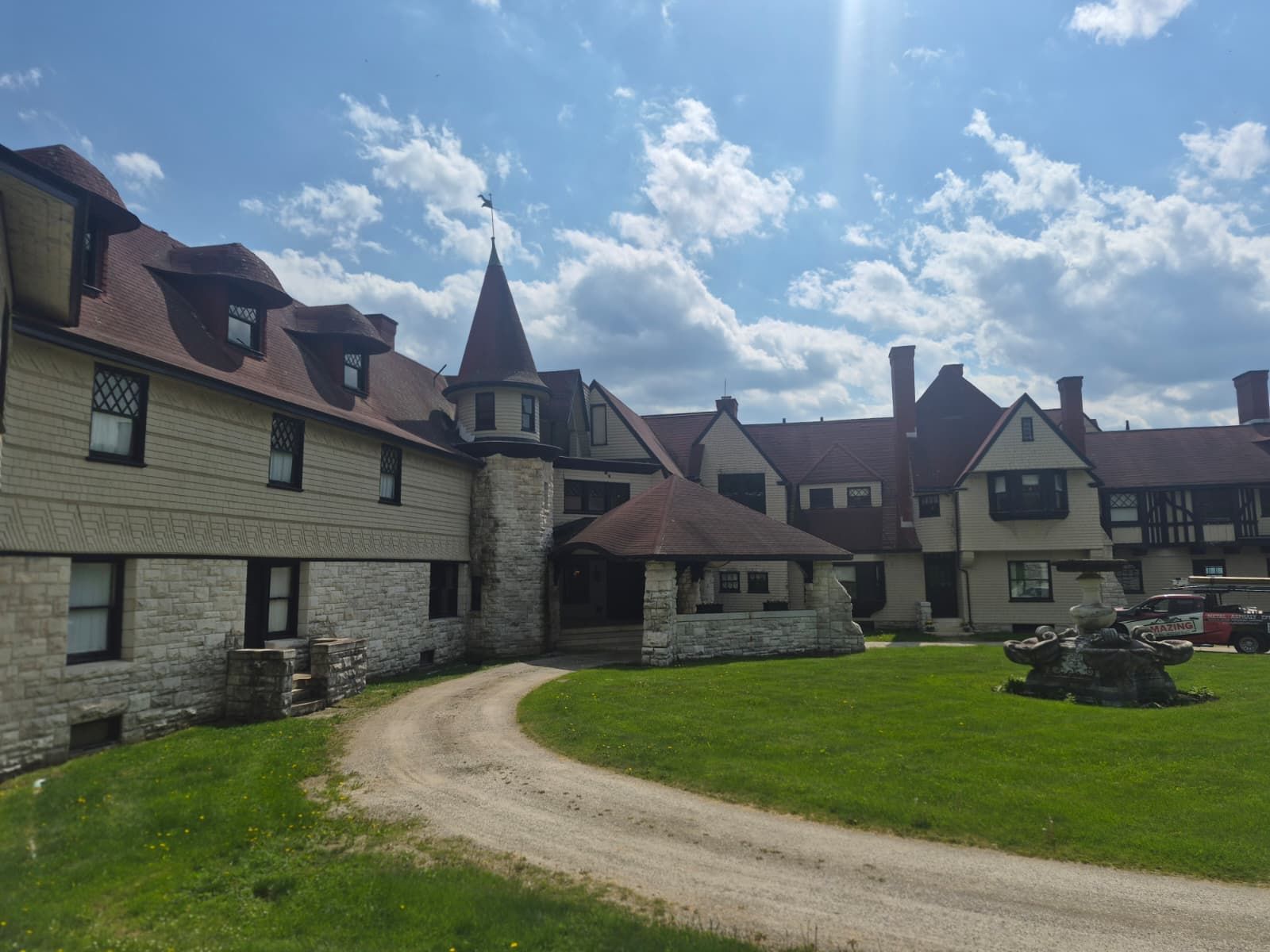 Stone courtyard buildings with red roofs and a winding path under a partly cloudy sky