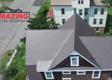 Aerial view of a house with a gray shingled roof and dormer, with a roofing company logo in the corner