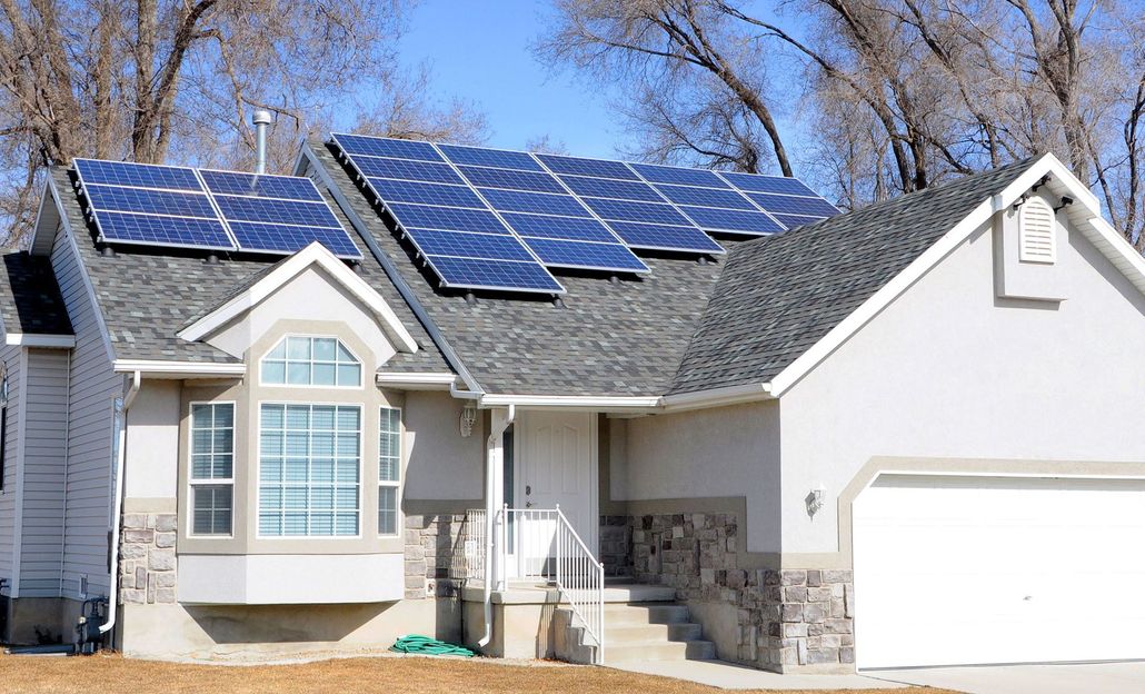 Suburban house with blue solar panels on the roof and a white garage door