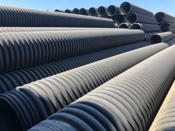 Black corrugated plastic pipes stacked outdoors.