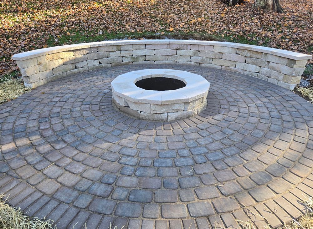 Circular stone fire pit and seating area in a backyard setting.