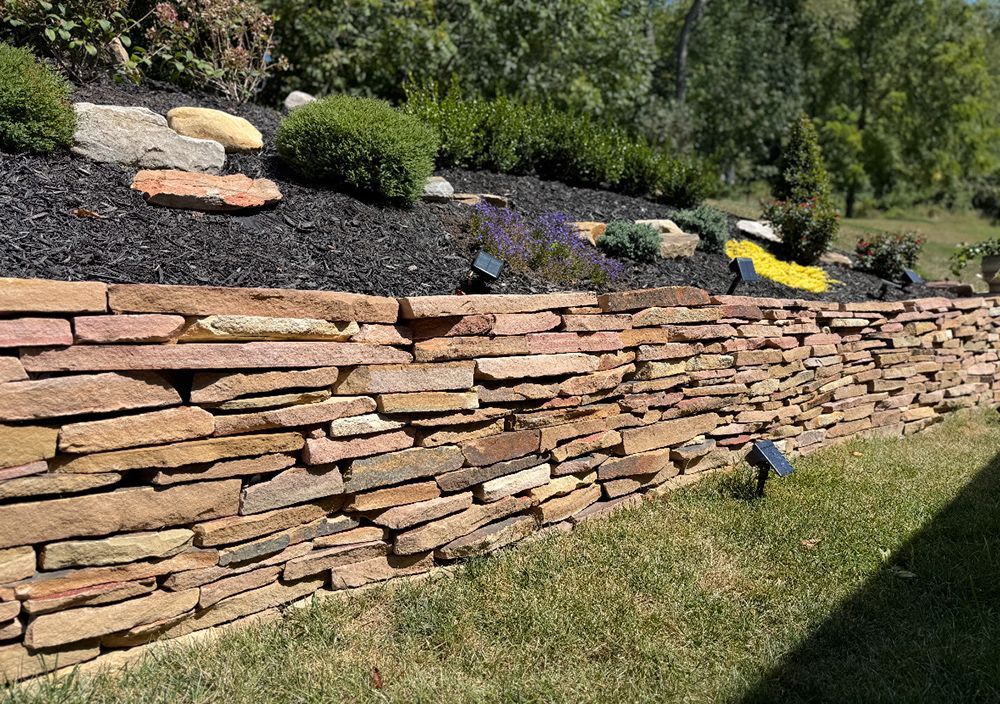 Stone retaining wall with a landscaped garden bed above.