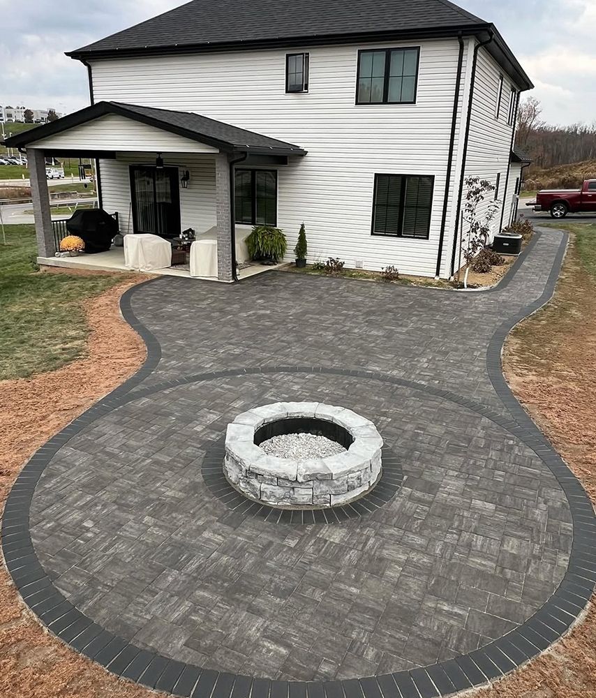 Paver patio with fire pit in front of a white two-story house.
