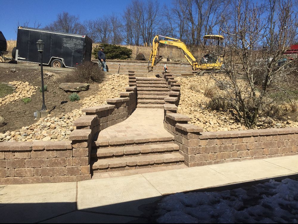 Brick staircase leading up a hill, with an excavator at the top, and a trailer on the left.