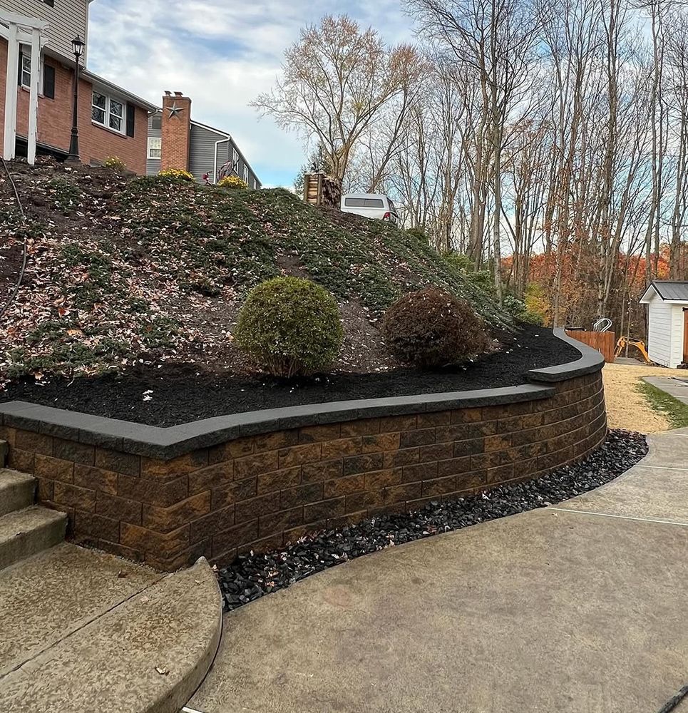 Brown retaining wall with a landscaped hillside and concrete steps.