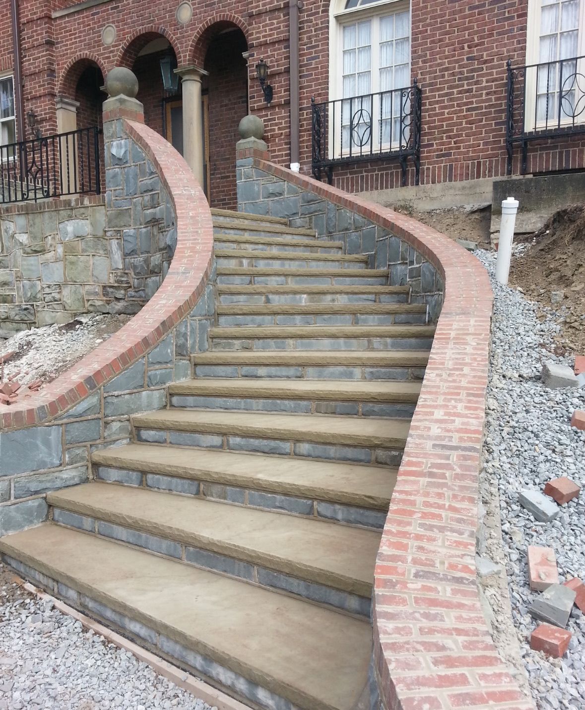 Brick and stone staircase leading up to a brick building; curved railing and stone accents.