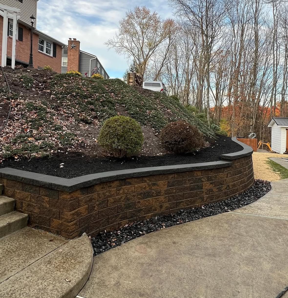 Brick retaining wall with landscaping and a sloped yard.