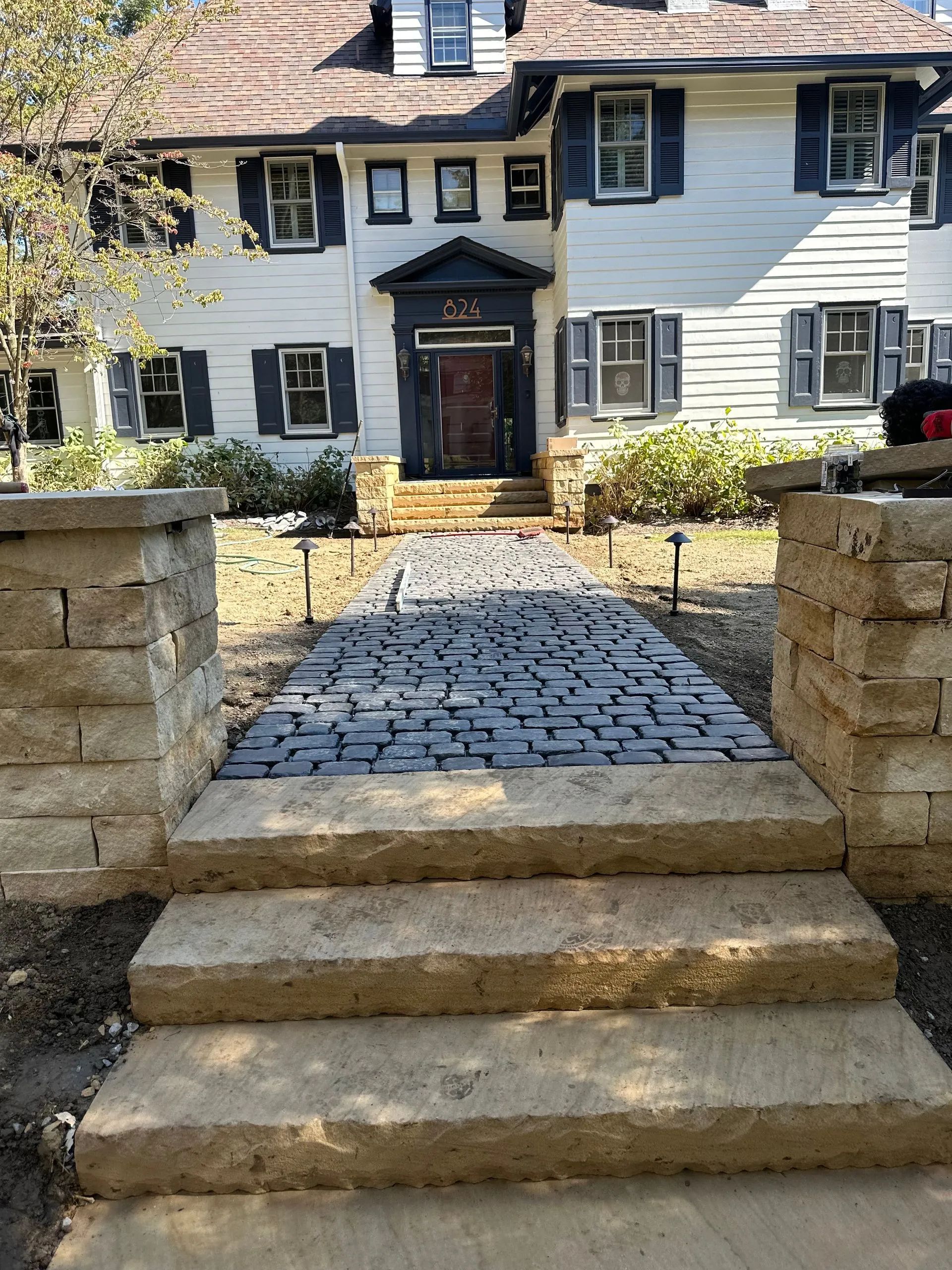 Stone steps and pathway leading to a white two-story house with blue shutters.