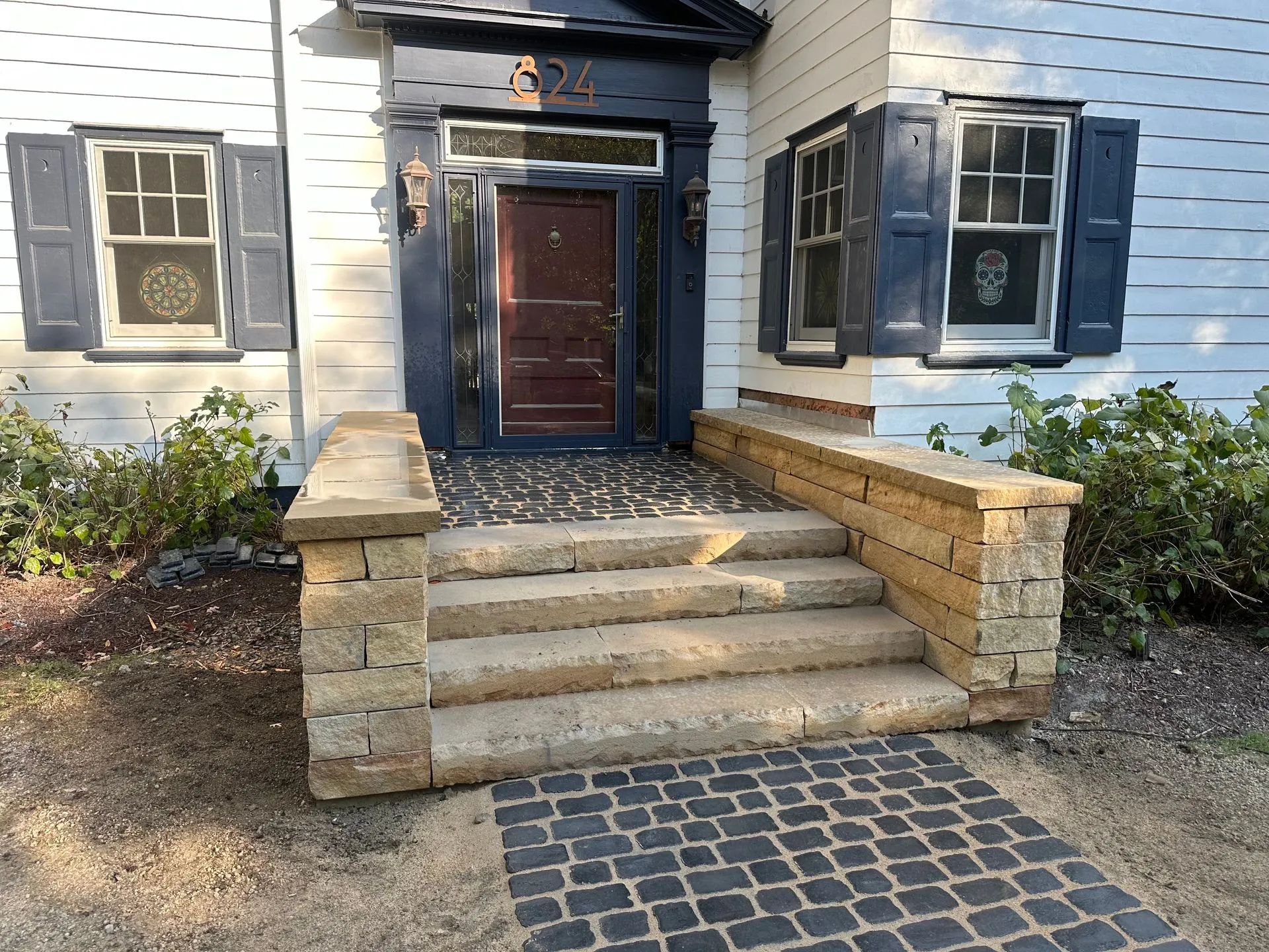 Stone steps leading up to a house with a dark blue door and blue shutters.