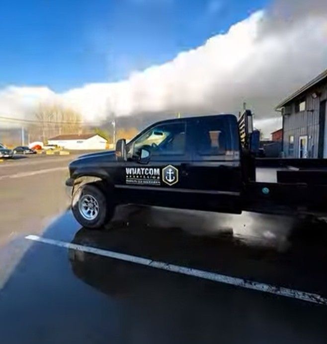 Black work truck parked on wet pavement; 