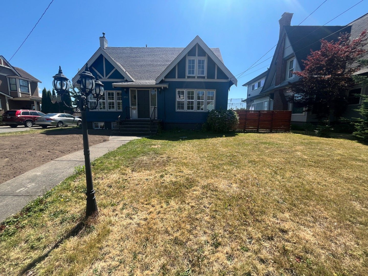 Blue house with light-colored trim and a small front yard; a sidewalk and a street are in front.