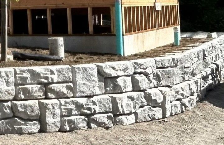 Stone retaining wall in front of a building with wooden siding.