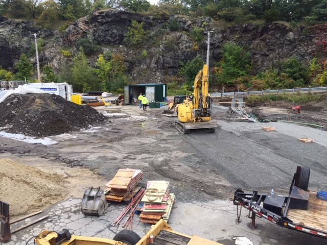 A construction site with a yellow excavator and a pile of dirt