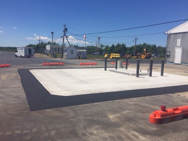 A wide parking lot with gray poles and house