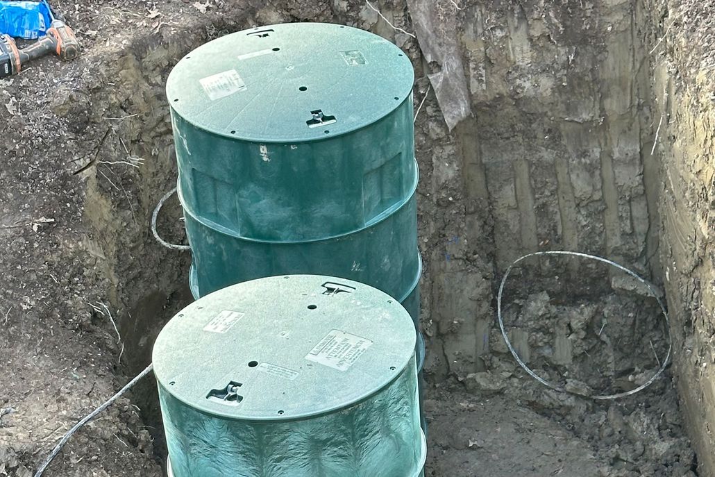 Two green cylindrical tanks in a dug-out pit against a dirt and rock wall