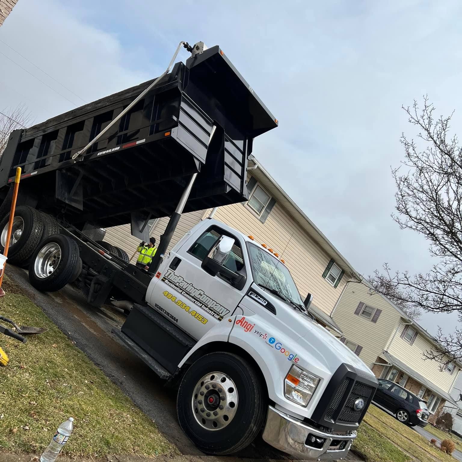 A dump truck is parked on the side of the road in front of a house.
