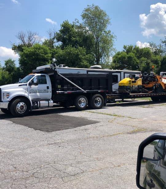 A truck is carrying a trailer with a snowmobile on it.