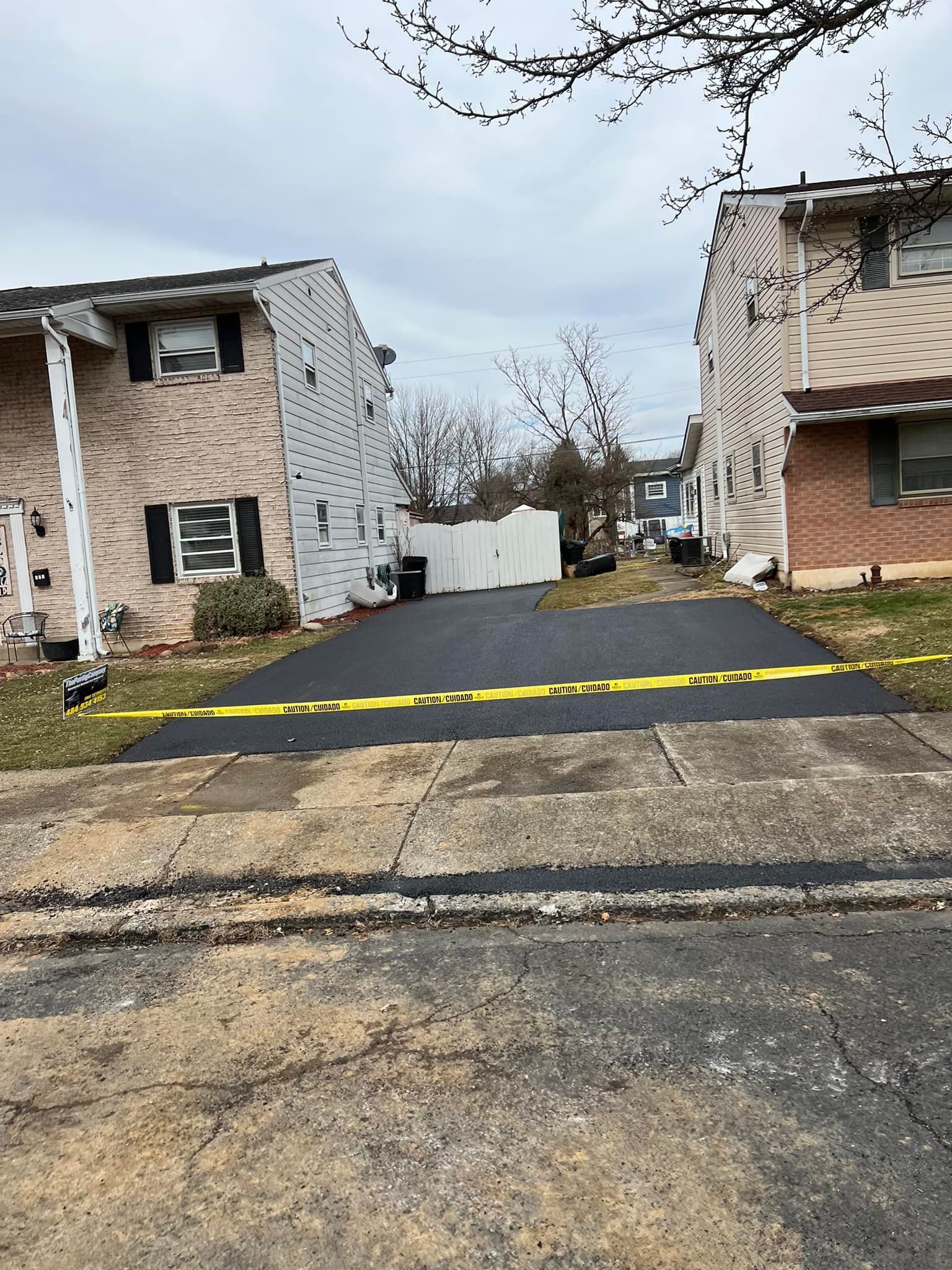 A newly paved driveway between two houses in a residential area.