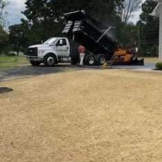 A dump truck is parked in a driveway next to a house.