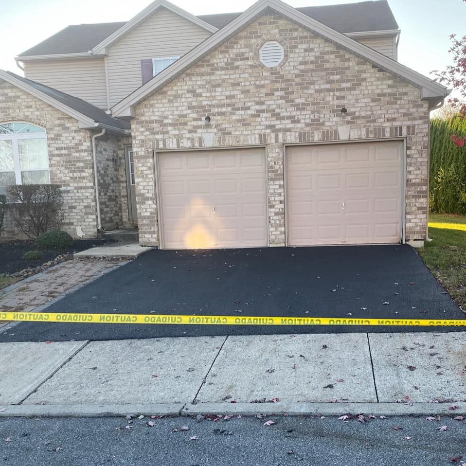 A brick house with two garage doors and a black driveway