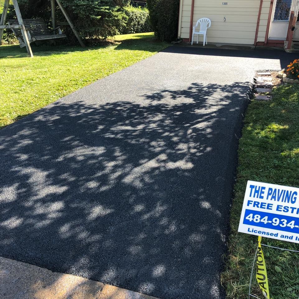 A sign for the paving company is on the side of a driveway.
