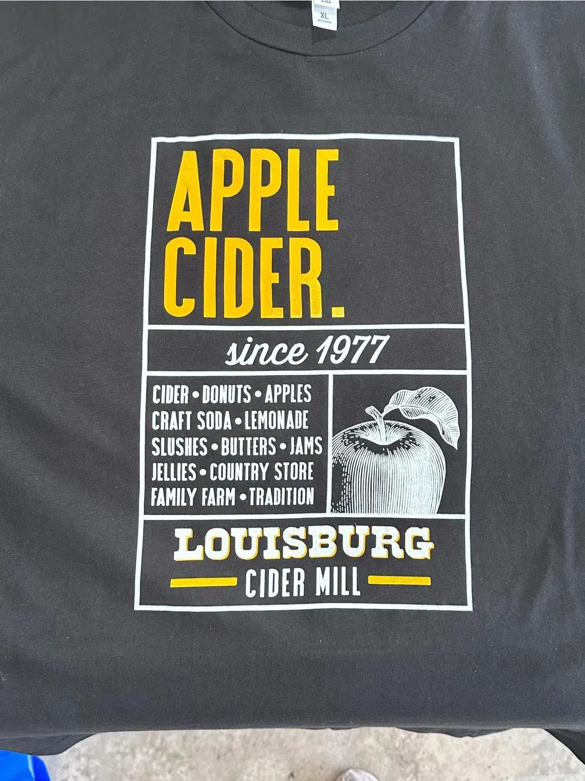 Black t-shirt with a white and yellow design for Louisburg Cider Mill. It says 