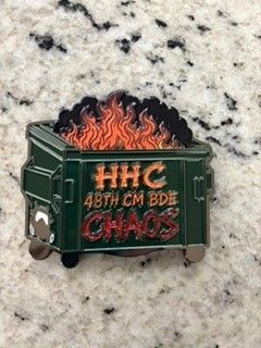 Green dumpster pin with flames and orange text reading “HHC 48TH CM BDE CHAOS”