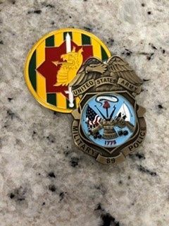Two military-style challenge coins, one red and yellow and one blue with an eagle emblem, on a speckled surface