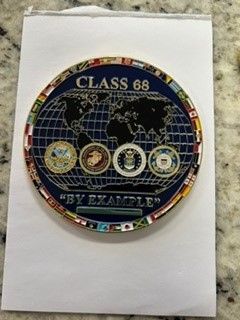 Circular Class 68 patch with a world map, gold border, and four smaller emblems at the bottom.