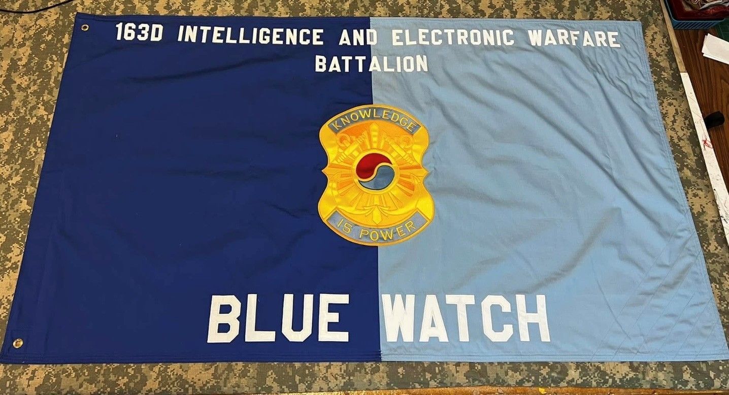 Blue military banner for the 1630 Intelligence and Electronic Warfare Battalion with a yellow insignia and “BLUE WATCH” text