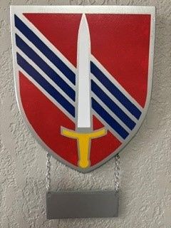 Red shield emblem with diagonal blue and white stripes and a white sword on a wall plaque