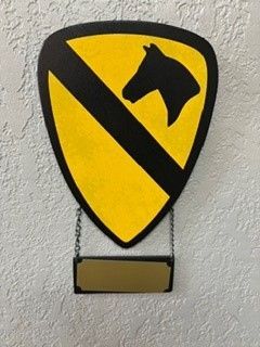 Yellow shield-shaped sign with black diagonal stripe and black star-like symbol, hanging on a wall with chain below