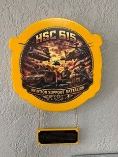 Round yellow wall plaque reading “HSC 615” and “Aviation Support Battalion” with military helicopters.