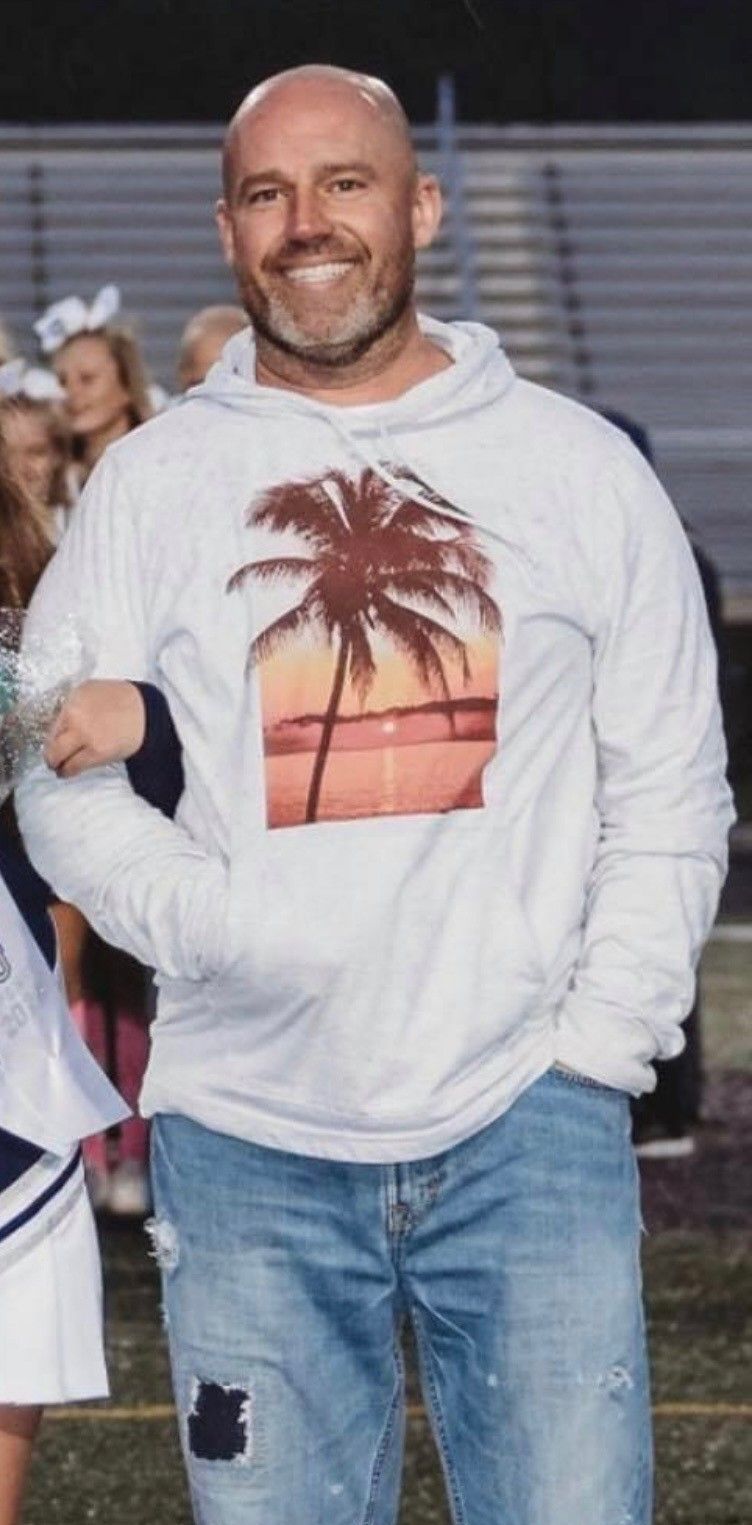 A man wearing a white hoodie with a palm tree on it.