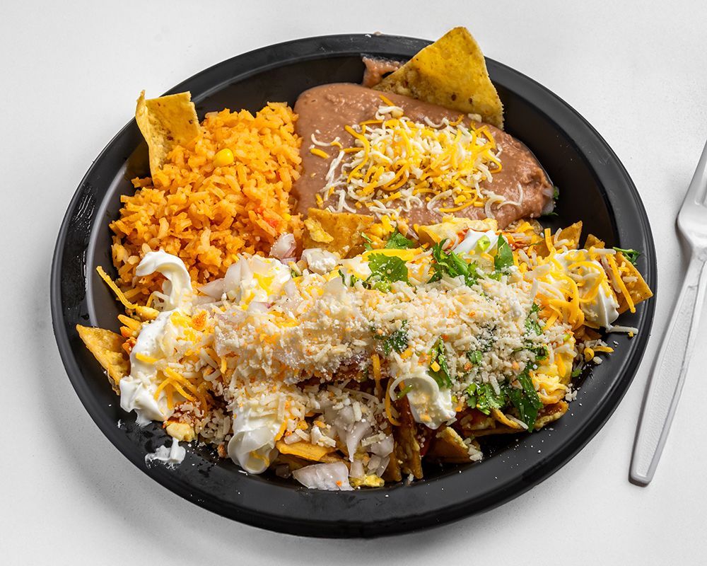 Plate of Mexican food: rice, beans, tortilla chips, eggs, cheese, and sour cream.