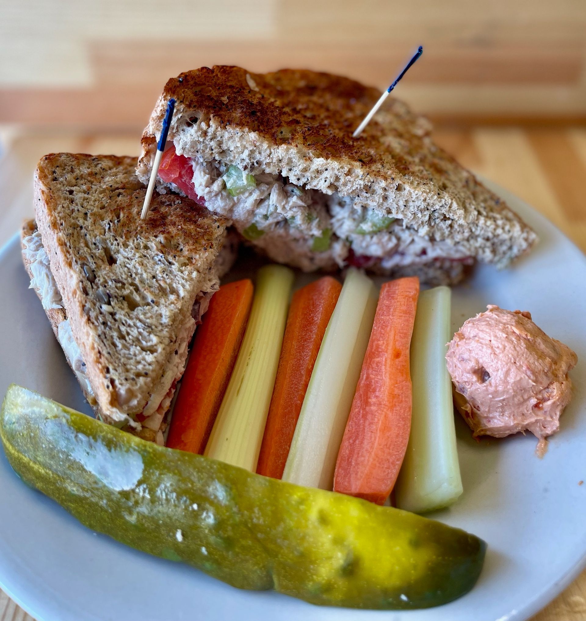 A sandwich with a pickle and carrots on a plate