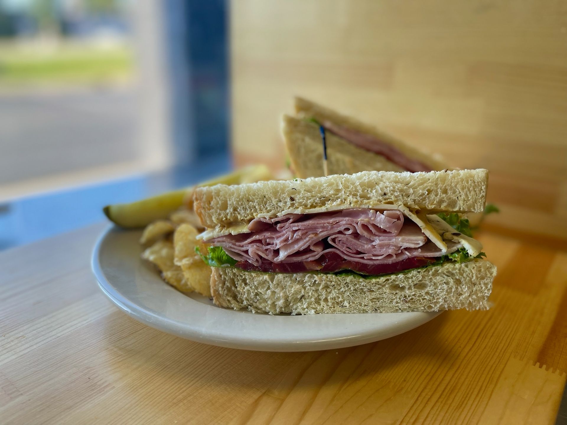 A club sandwich and french fries on a white plate on a wooden table.