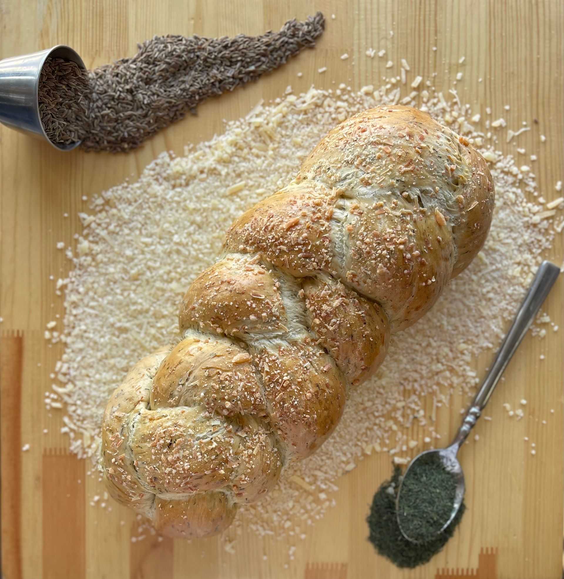 A loaf of bread is sitting on a wooden cutting board next to a spoon.