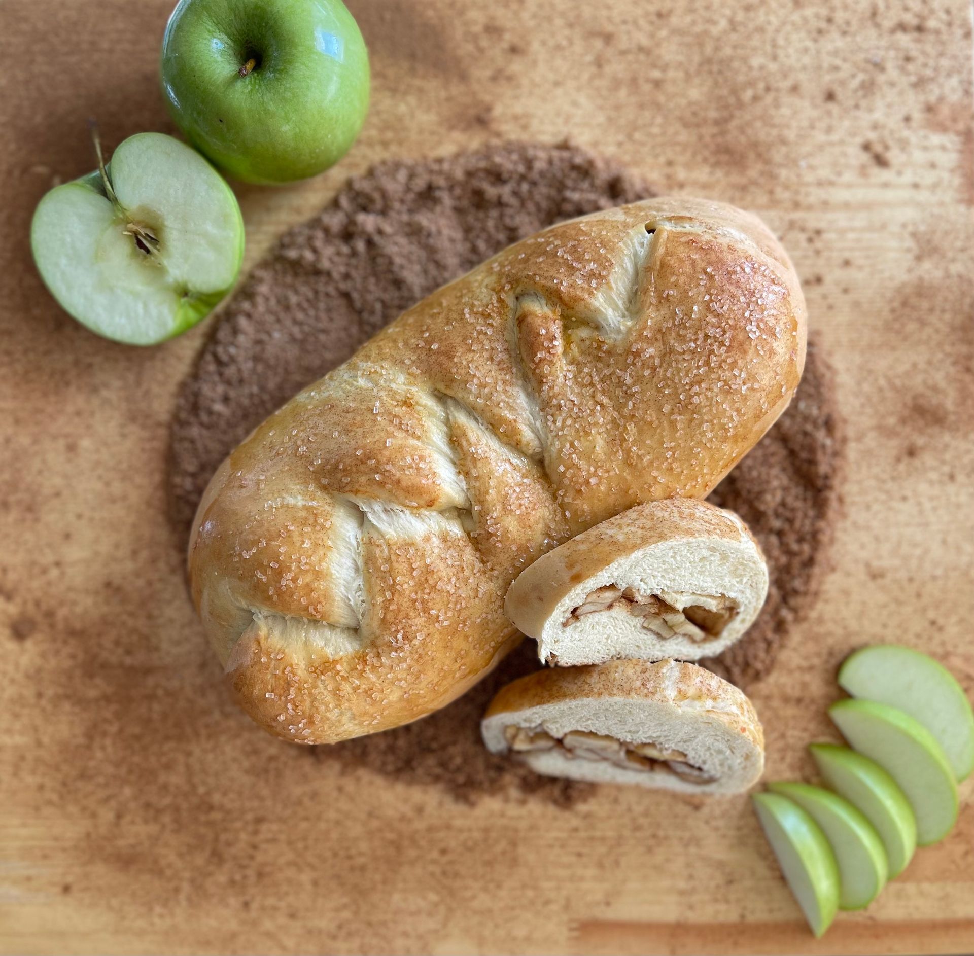 A loaf of bread is sitting on a wooden cutting board next to apples.